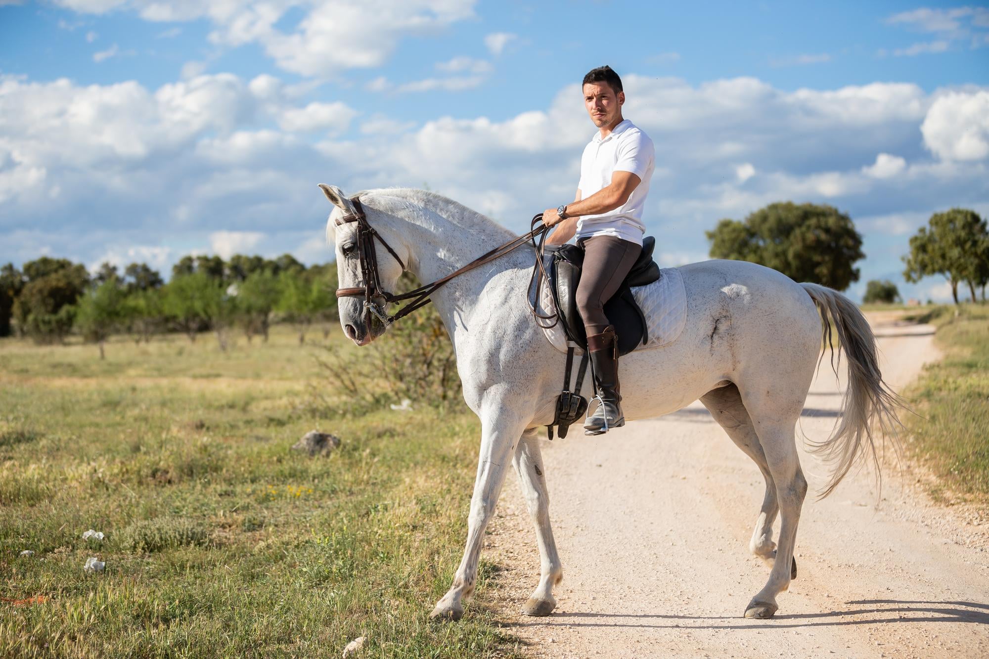Hombre montando a caballo al paso por el campo