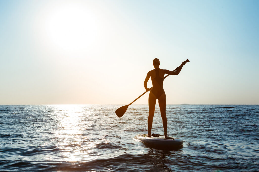 Mujer haciendo paddle surf en la playa