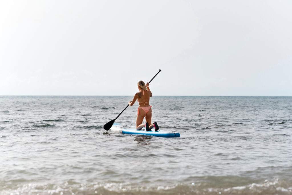 Mujer haciendo paddle surf en la playa