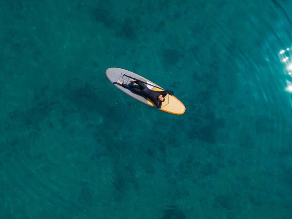 Hombre tumbado relajado sobre una tabla de paddle surf