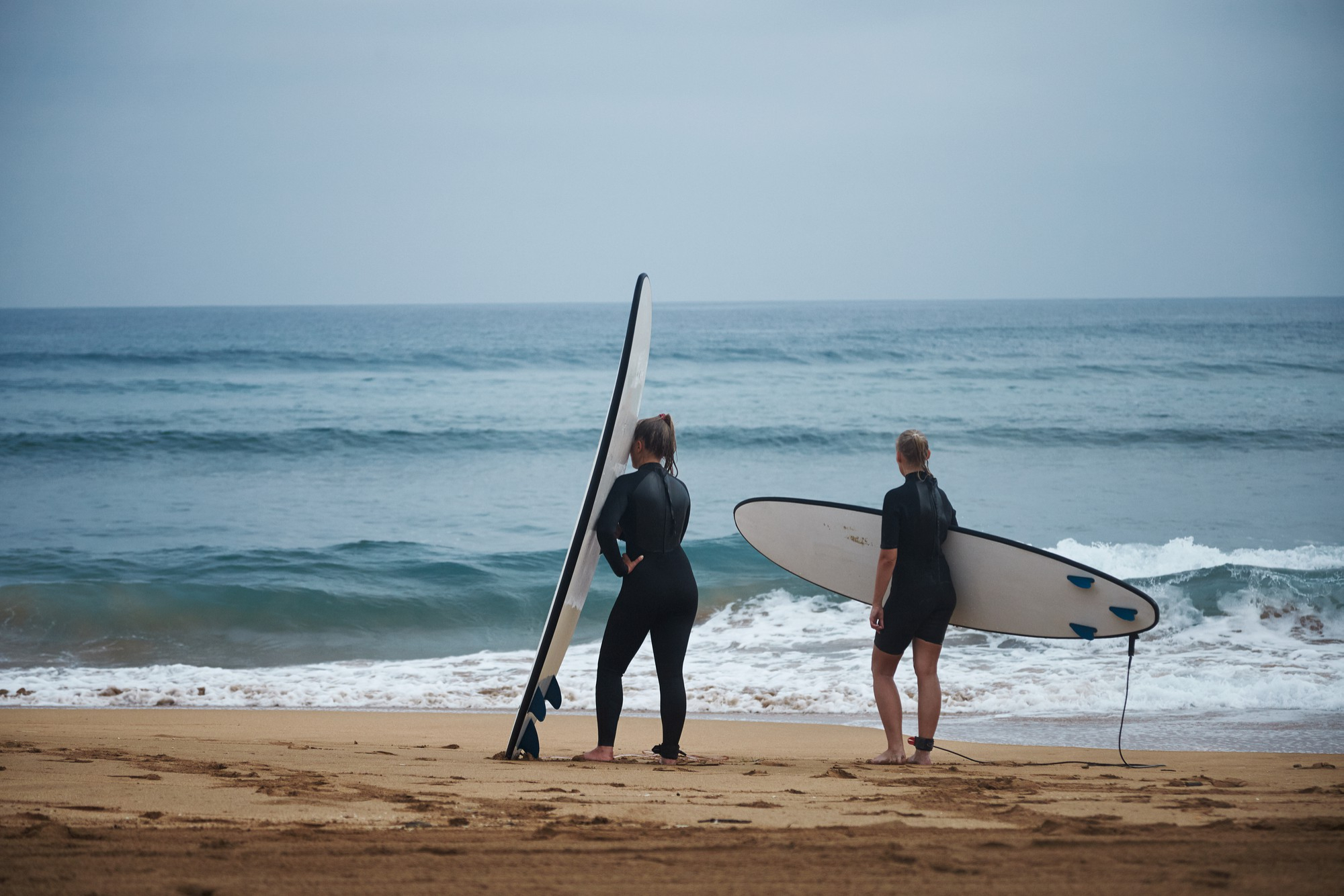 Dos personas con tablas de paddle surf frente a una playa
